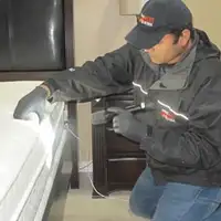 Bed bug inspection technician checking a mattress and bed frame for signs of infestation in Staten Island, NY