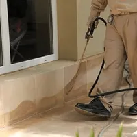 General pest control technician spraying exterior perimeter around a home in Staten Island, NY