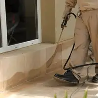 General pest control technician spraying exterior perimeter around a home in Staten Island, NY