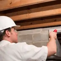 Termite inspection technician checking a basement wall and framing for termite activity in Staten Island, NY